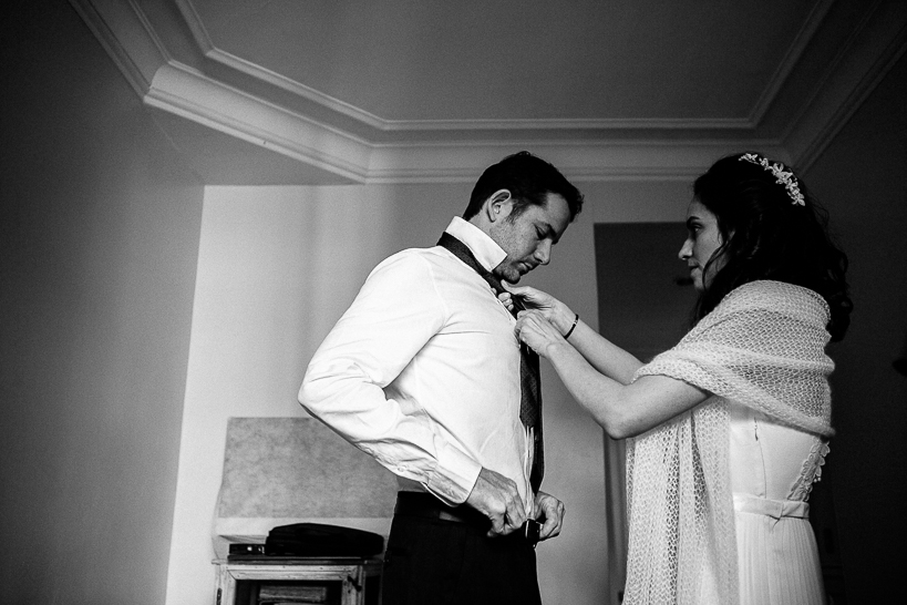 photo en noir et blanc de la mariée aidant le marié avec sa cravate